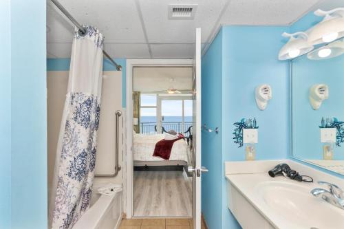 a bathroom with blue walls and a tub and a sink at Amazing Oceanfront Home HS 4th Floor in Myrtle Beach
