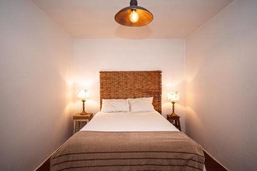 a bedroom with a bed with two lamps on both sides at Cá Ficamos - T1 Hortacasa Portugal in Santiago do Cacém
