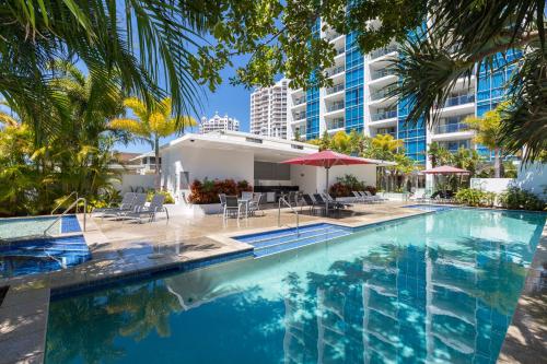 a swimming pool with chairs and umbrellas and a building at Ocean Pacific Resort - Official in Gold Coast
