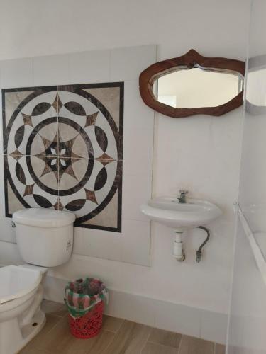 ein Badezimmer mit Toilette, Waschbecken und Spiegel in der Unterkunft Fiesta Zipolite in Zipolite