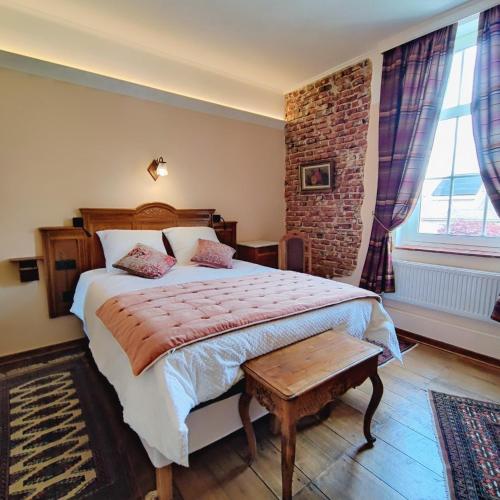 a bedroom with a bed and a brick wall at La Porte Noire in Courcelles