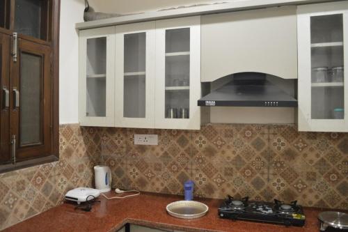 a kitchen with white cabinets and a counter top at Ananta 1BHK in Birbhaddar