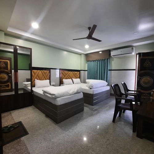 a bedroom with two beds and a ceiling fan at Surakha INN LLP in Siliguri