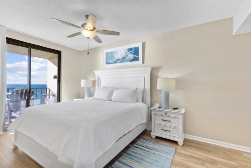 a white bedroom with a bed and a ceiling fan at Phoenix X Unit 1512 in Orange Beach