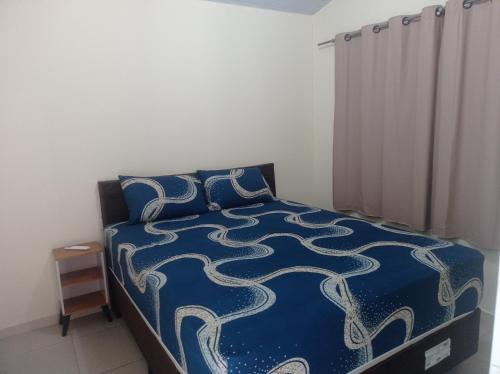 a bedroom with a bed with a blue comforter and pillows at Recanto do Garças in Aragarças