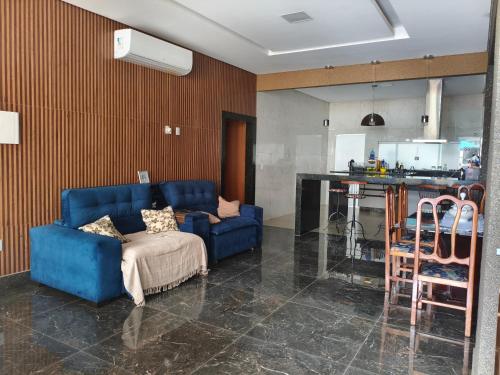 a living room with a blue couch and a kitchen at Paraíso do aconchego in Aparecida de Goiânia