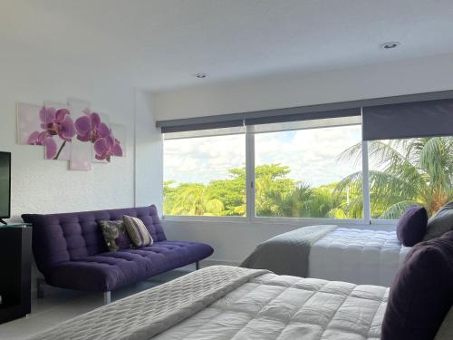 a bedroom with a bed and a purple couch and a window at Divine Suite Cancun - BEACH CONDO - 6PX in Cancún