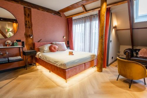 a bedroom with a bed and a mirror and a chair at Boetiekhotel Faan in Ballum