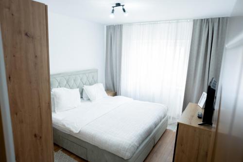 a bedroom with a white bed and a window at Apartament centru in Râmnicu Vâlcea