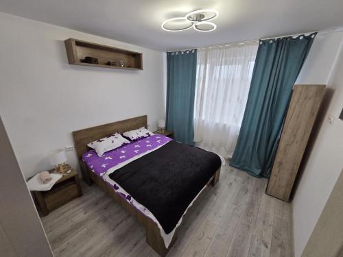 a bedroom with a bed with purple sheets and blue curtains at NGR Residence in Ploieşti