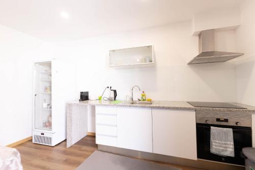 a white kitchen with a sink and a stove at Trajadinha do Lima Rooms in Ponte de Lima