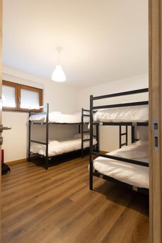 three bunk beds in a room with wooden floors at Trajadinha do Lima Rooms in Ponte de Lima