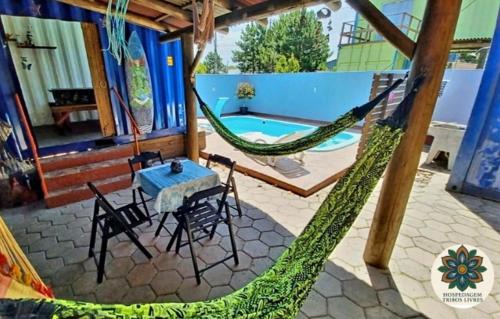 a patio with a hammock and a table and chairs at Hospedagem Tribos Livres in Torres