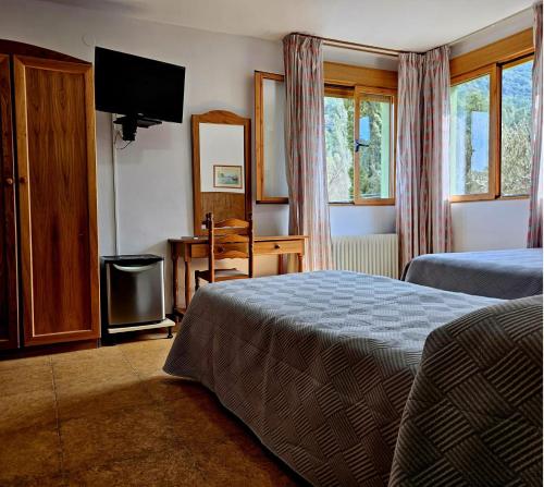 a bedroom with a bed and a desk and a television at Hotel Rural Montaña de Cazorla in Arroyo Frio