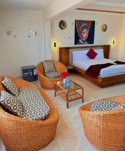 a bedroom with a bed and two wicker chairs at MAG Palace Hotel in Bissau