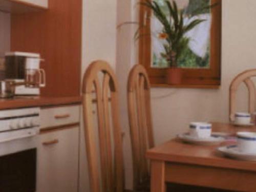 a kitchen with two wooden chairs and a wooden table at Ferienwohnung mit Loggia im Teutoburger Wald in Bredenborn
