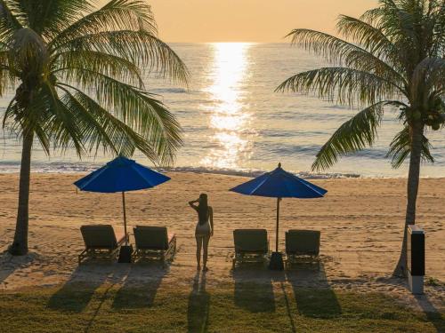 a woman standing under two umbrellas on a beach at SO/ Sofitel Hua Hin in Cha Am