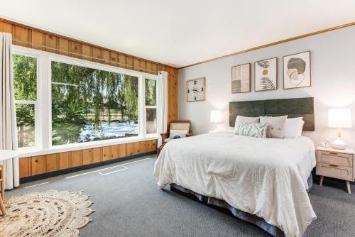 a bedroom with a bed and a large window at Ground Floor River Front Studio Cottage in Bend