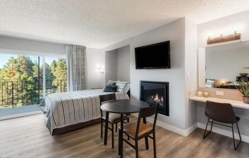 a bedroom with a bed and a table and a fireplace at Updated Condo with Deschutes River View in Bend
