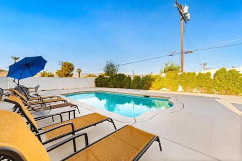 a swimming pool with chairs and an umbrella at Cozy Retreat with Pool, BBQ and Fire Pit in Indio