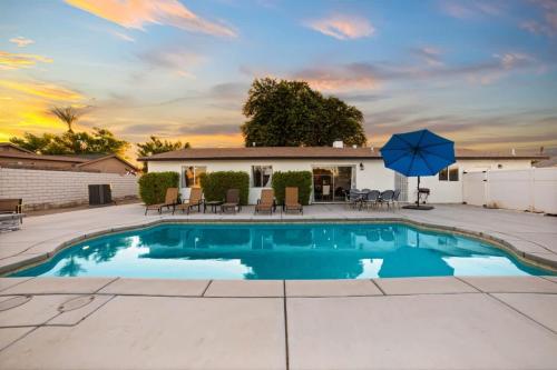 a pool with chairs and an umbrella in a yard at Cozy Retreat with Pool, BBQ and Fire Pit in Indio