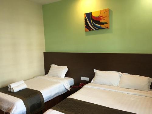 um quarto com duas camas e um quadro na parede em Lintas Plaza Hotel em Kota Kinabalu