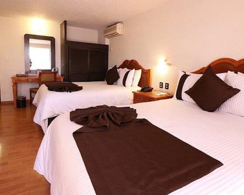 a hotel room with two beds and a mirror at Hotel Vilamiño in Aguascalientes