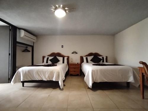 a bedroom with two beds with white sheets and a light at Hotel Vilamiño in Aguascalientes