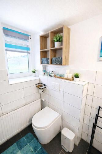 a white bathroom with a toilet and a window at Ferienwohnung Saupe in Königshain