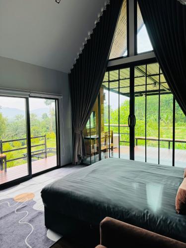 a bedroom with a large bed and large windows at เขากิวเทอเรส @สิชล in Sichon