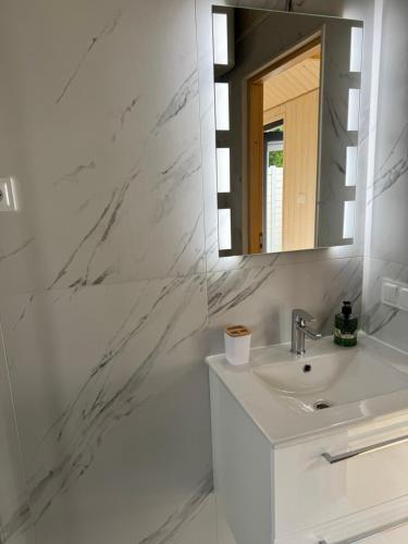 a white bathroom with a sink and a mirror at Sosnowe Zacisze in Dębki