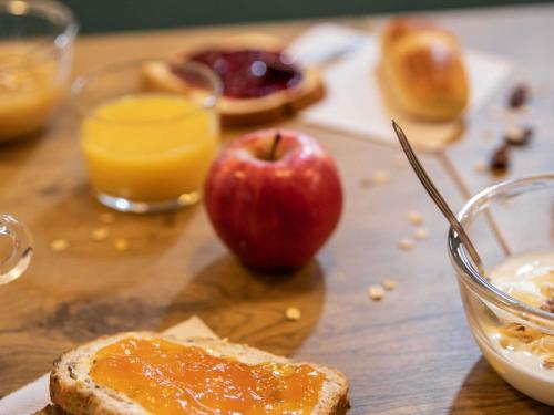 a table with an apple and a piece of bread and orange juice at hotelF1 Merlebach Saarbrueck in Merlebach