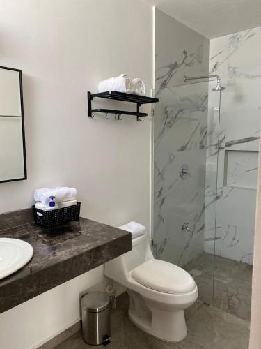 a bathroom with a toilet and a glass shower at Otoch de Paz in Cholul