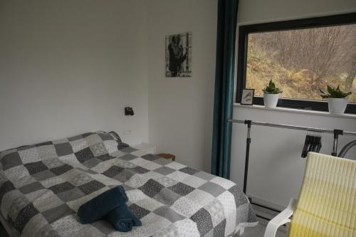 a bedroom with a bed with a checkered blanket and a window at Chatka Bratka in Kletno