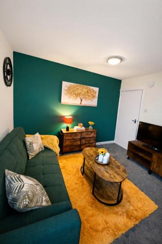 a living room with a green couch and a table at Harbour Lights Retreat-Small and Cosy 1 bedroom in Ferryden