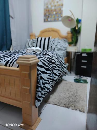 a bedroom with a bed with black and white sheets at Adem Cozy Home in Abu Dhabi