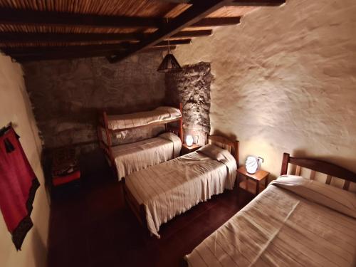 a bedroom with two beds and a stone wall at Posada Las Piedras in Tilcara