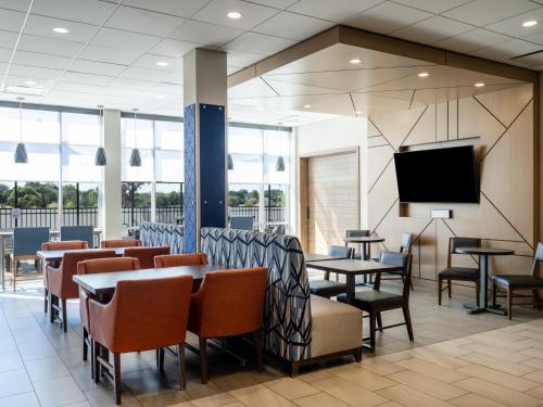 a restaurant with tables and chairs and a flat screen tv at Holiday Inn Express & Suites - Meridian - Boise West by IHG in Meridian