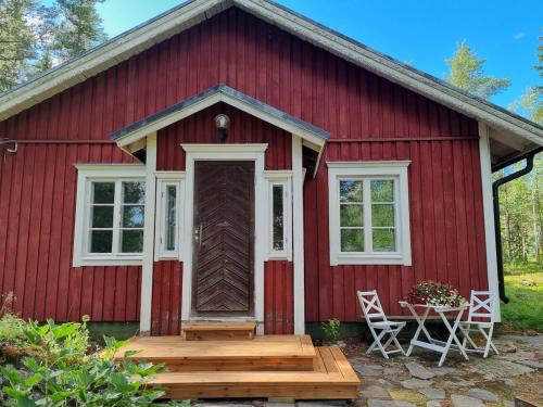 a red barn with a wooden door and two chairs at The River House & Riverside Sauna in Kokkola