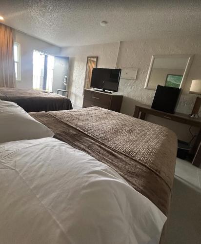 a hotel room with two beds and a flat screen tv at Gardenview Motel in Tampa