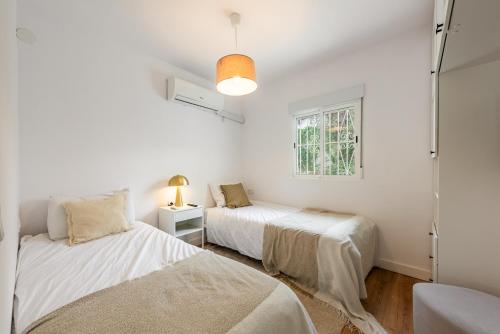 two beds in a white room with a window at Cozy Villa With Pool In Marbella Nueva Andalucia in Marbella