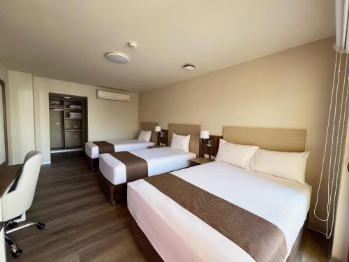 a hotel room with two beds and a desk at DM Hoteles Nasca in Nazca