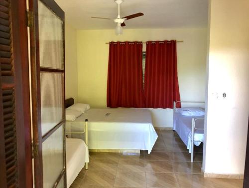 a room with two beds and a window with red curtains at Spin world Clube São Roque in São Roque