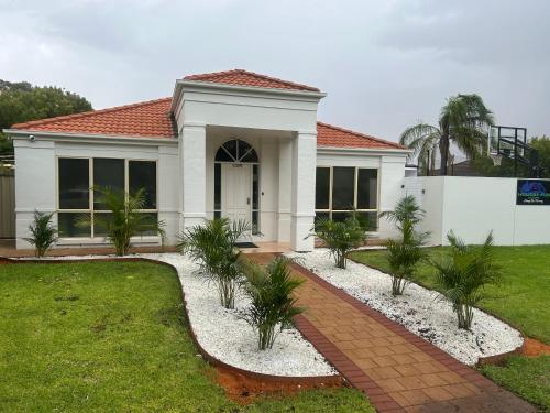 a white house with palm trees in front of it at Holiday fun mildura family retreat in Mildura