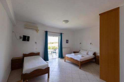 a bedroom with two beds and a sliding glass door at Kipriotis Hotel in Arkoudi