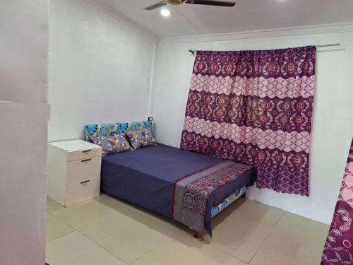 une petite chambre avec un lit et un rideau dans l'établissement Singhs, à Nadi