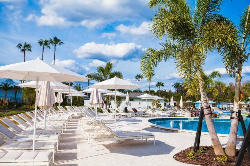 a pool with white lounge chairs and umbrellas at Golf Coast Bleu III - 3158-3160 in Zephyrhills