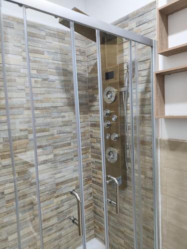 a shower in a bathroom with a stone wall at Heidi's home in Villabate