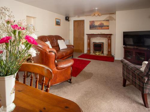 a living room with leather furniture and a fireplace at The Bridge Inn Apartment in Bridgerule