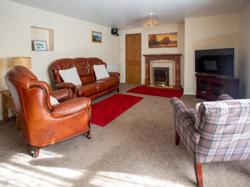 a living room with leather furniture and a fireplace at The Bridge Inn Apartment in Bridgerule